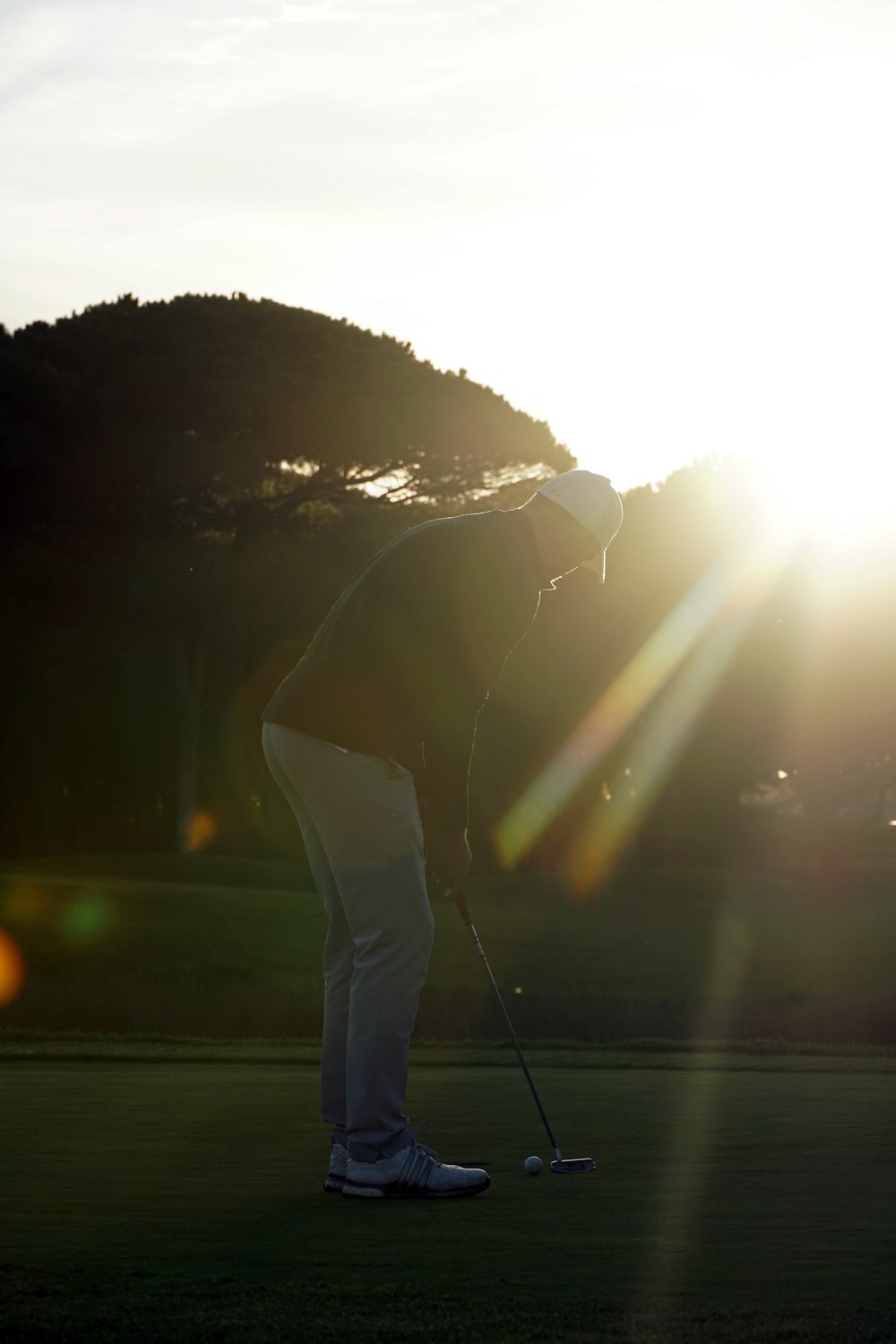 太陽を背景にゴルフコースにいる人