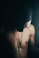 a shirtless man with a necklace on his chest