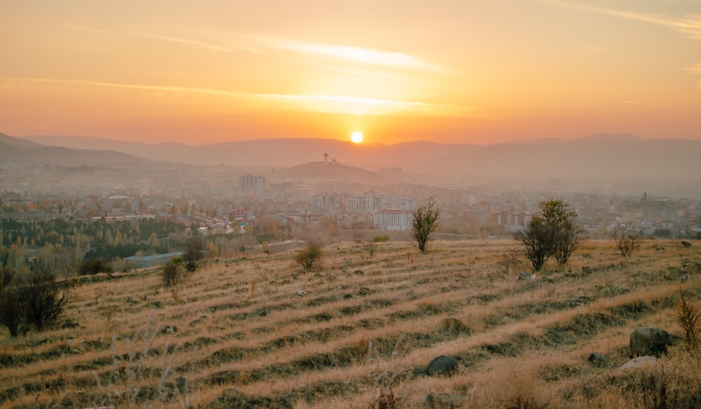 the sun is setting over a city in the distance