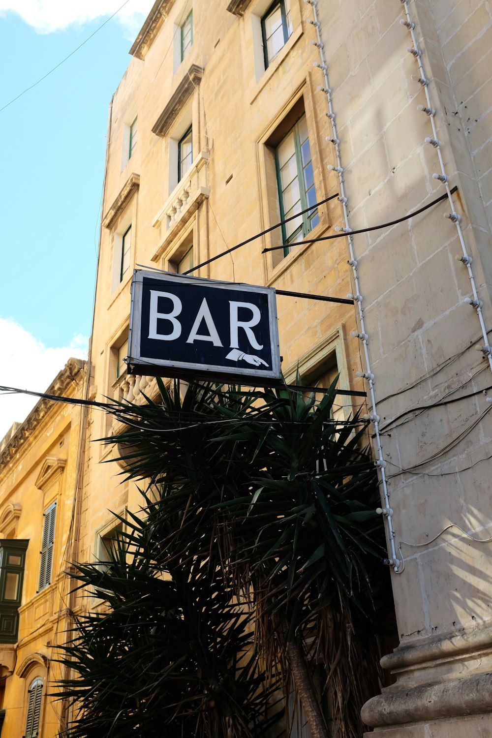 a bar sign hanging off the side of a building