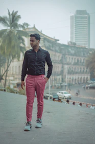 A confident man wearing a sleek, soft pink-accented outfit in a city setting.