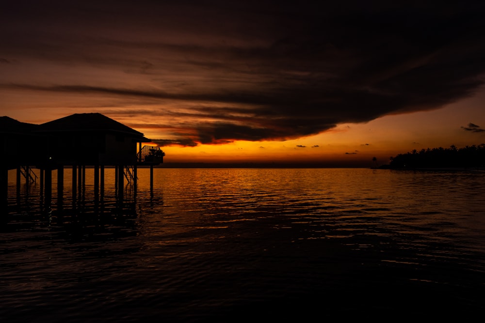 a house sitting on top of a body of water under a cloudy sky