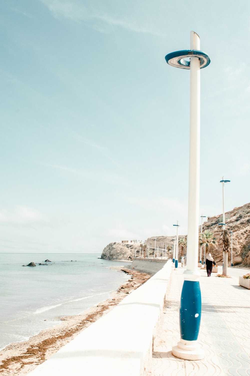a blue and white light pole sitting on the side of a beach
