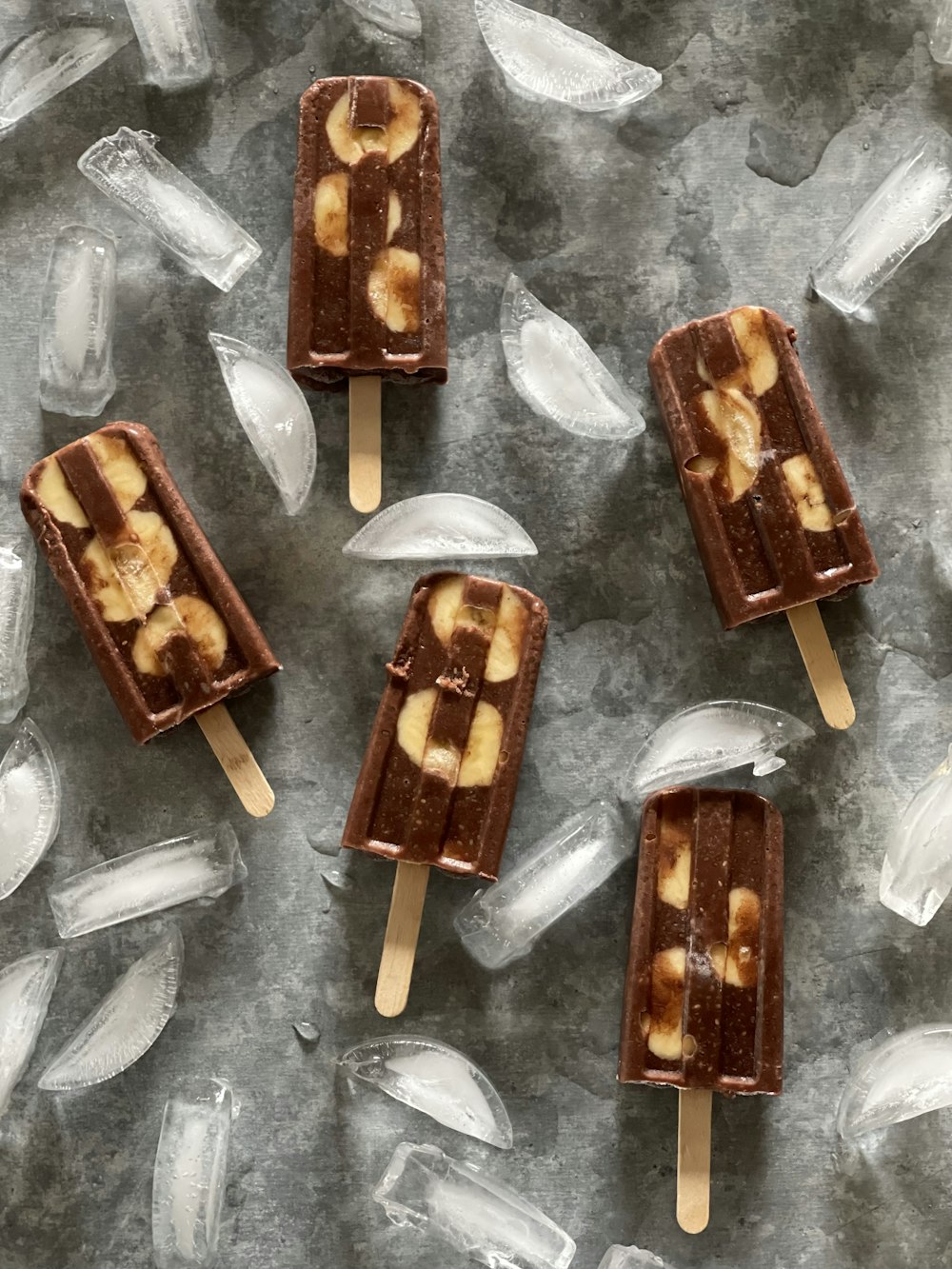 four pieces of chocolate and banana pops on ice