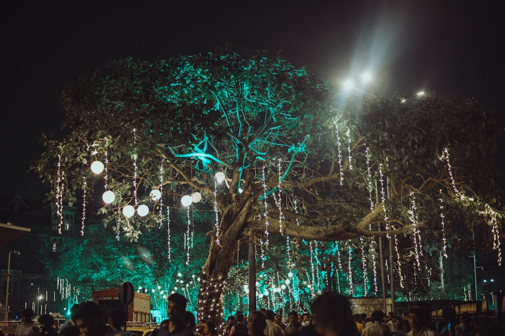 a group of people standing around a tree covered in lights