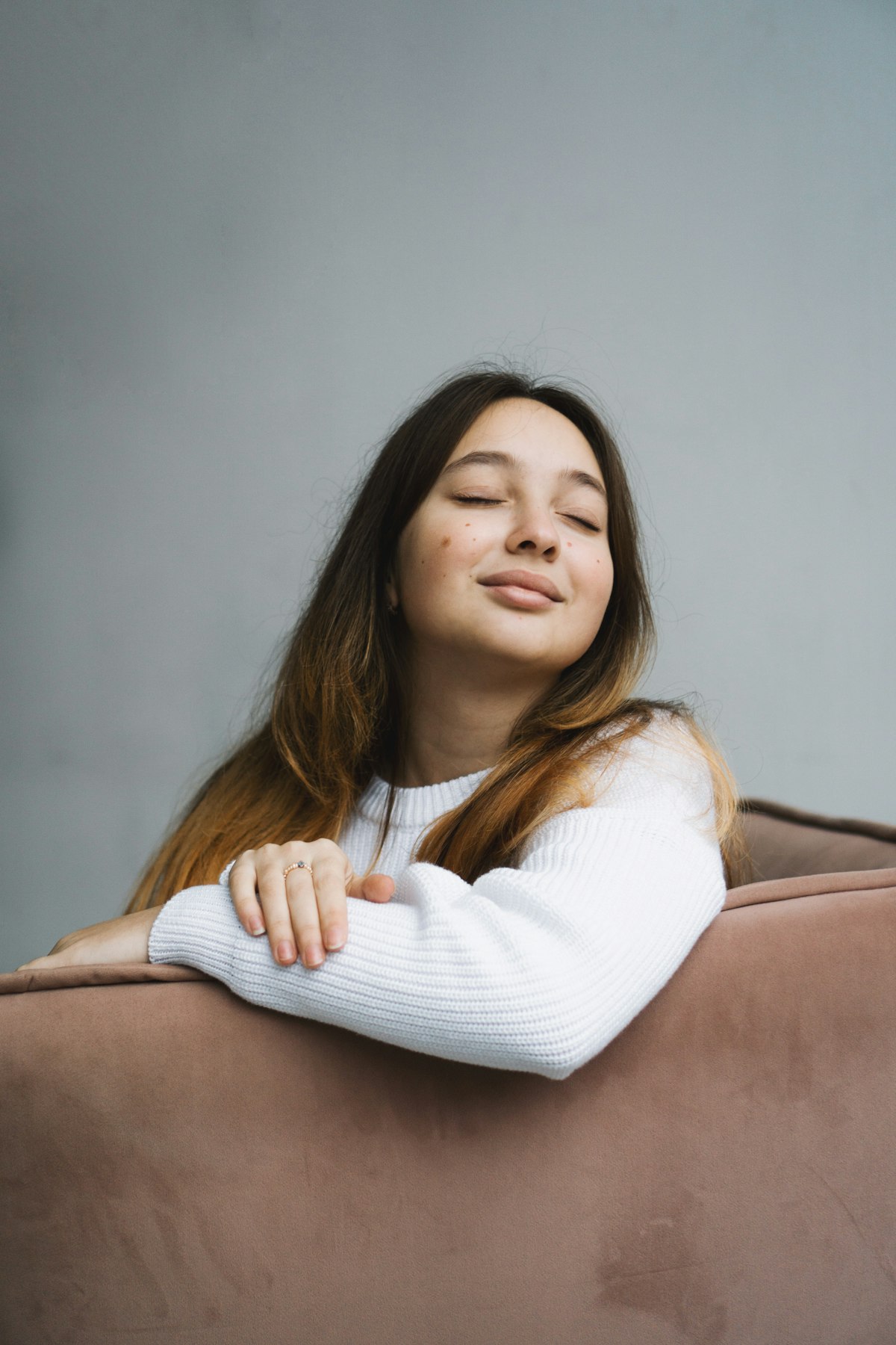 Young woman resting on a couch with eyes closed in soft daylight, calm interior moment