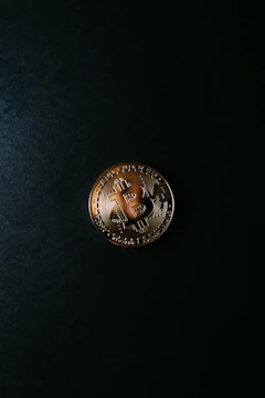 Close-up of a golden Bitcoin resting on a velvet cushion under soft lighting.