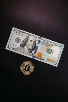 a one dollar bill and a bitcoin on a table