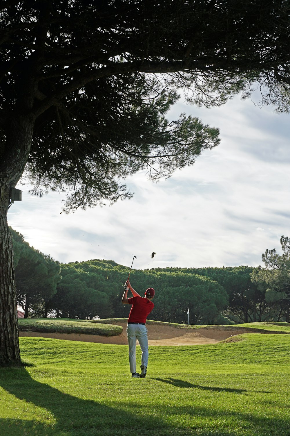 a man swinging a golf club in a park