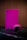 A gaming console and controller, both in a vibrant pink color, are placed on a dark reflective surface. The background consists of vertical wooden panels, providing a warm contrast to the bright gaming equipment.