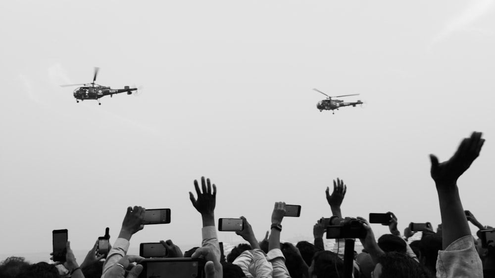 a crowd of people holding up their cell phones in front of a helicopter