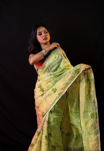 A soft pastel-colored chiffon saree with delicate floral embroidery displayed against a minimalist white background.
