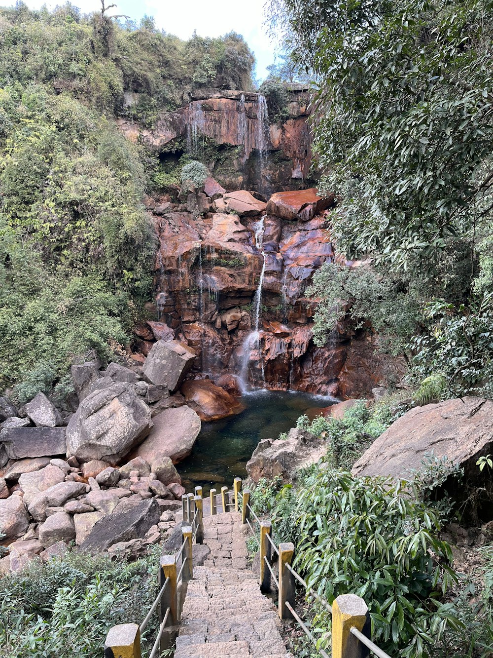 stairs lead up to a waterfall with a waterfall in the background