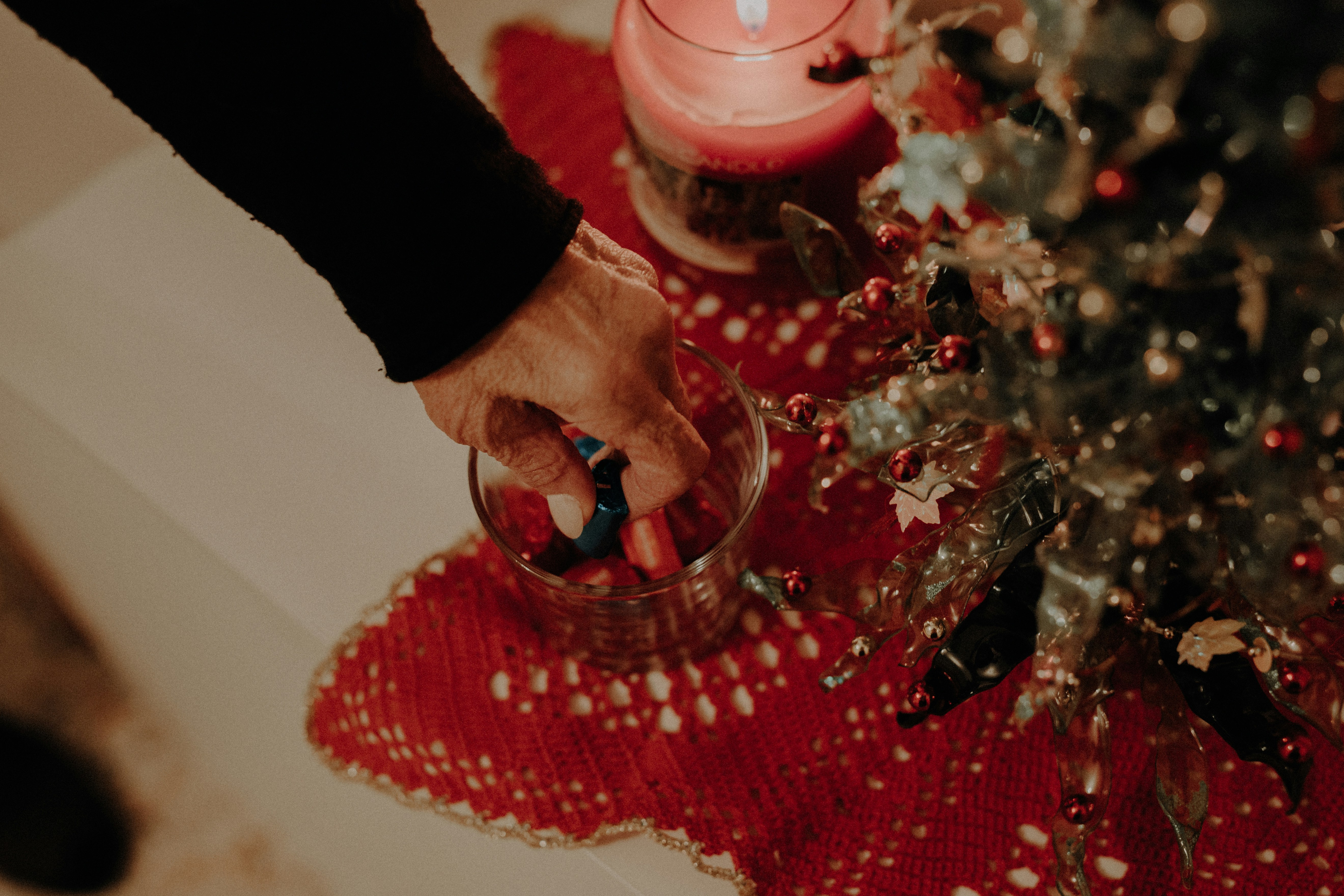 a person is holding a candle near a christmas tree