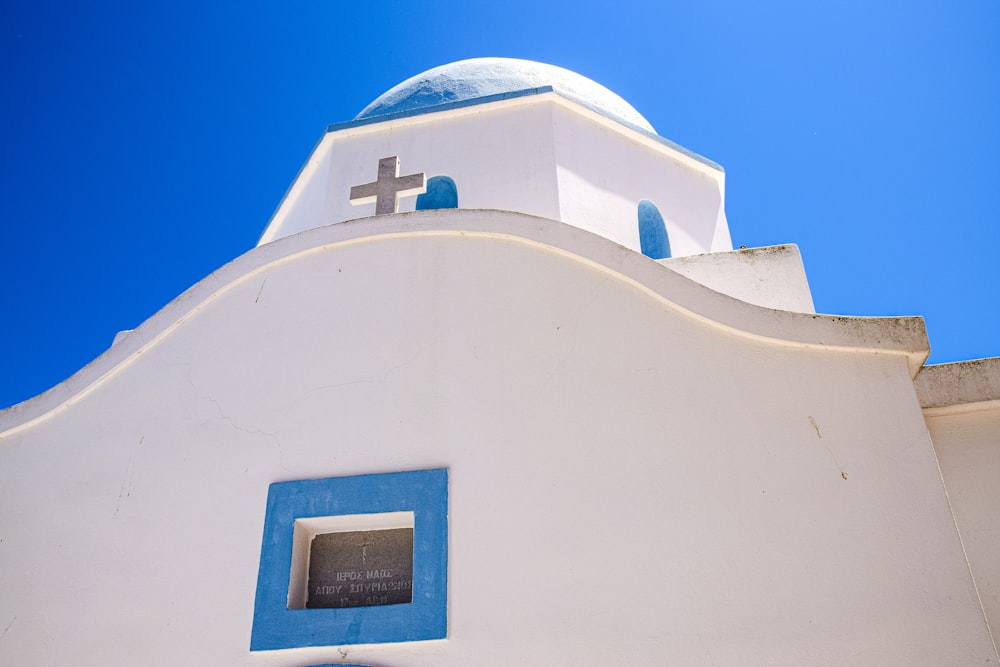 a white building with a blue window and a cross on it