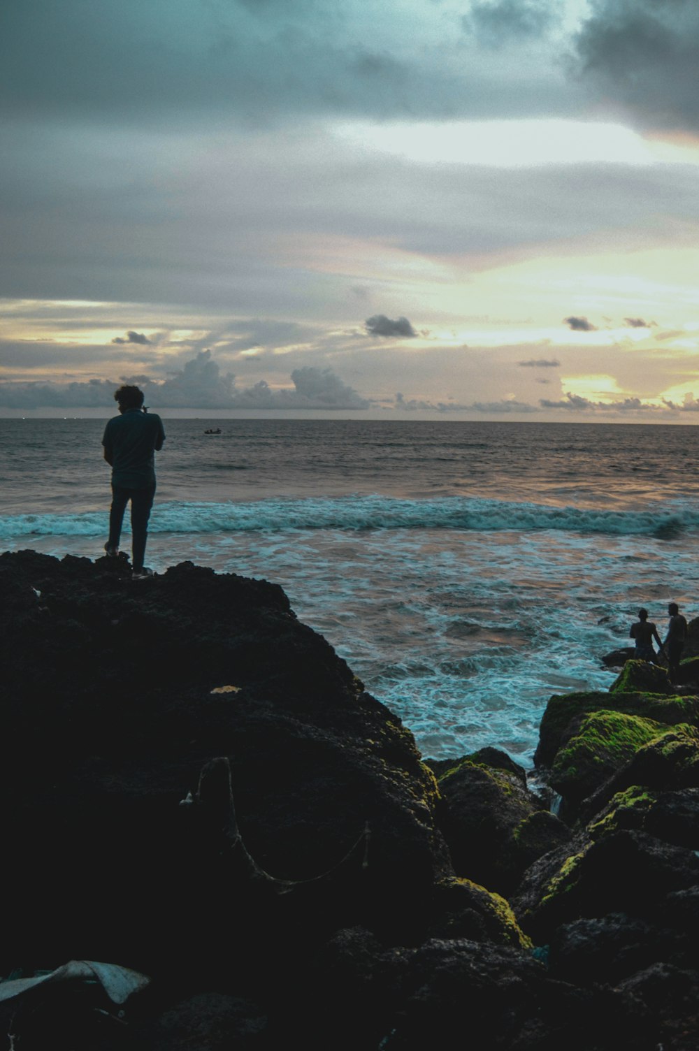 a man standing on top of a rock next to the ocean