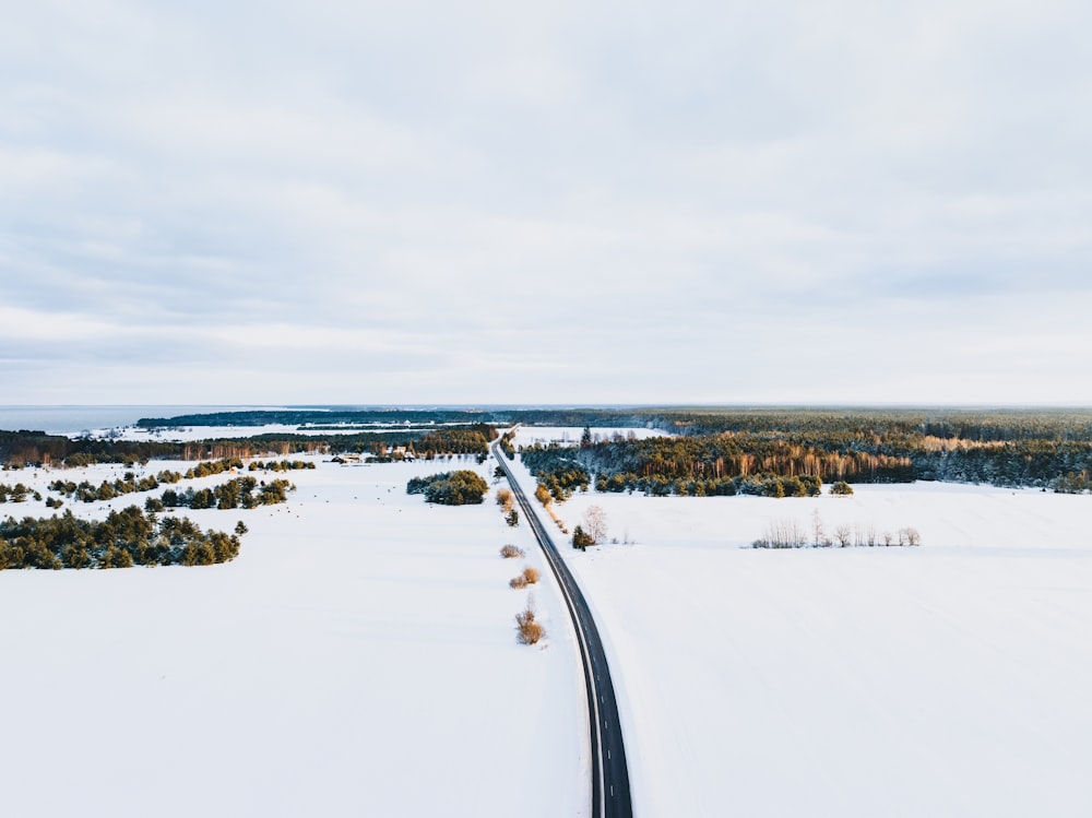 a road in the middle of a snowy field