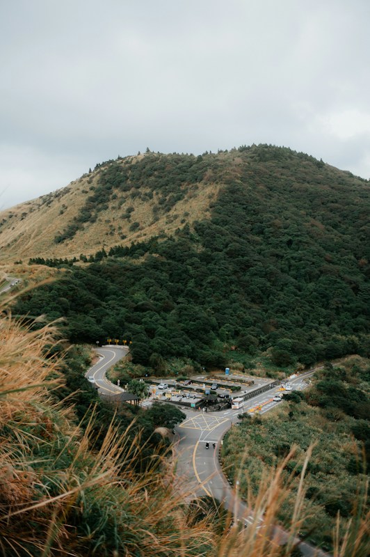 陽明山國家公園的山坡與蜿蜒山路，山腳下有停車場