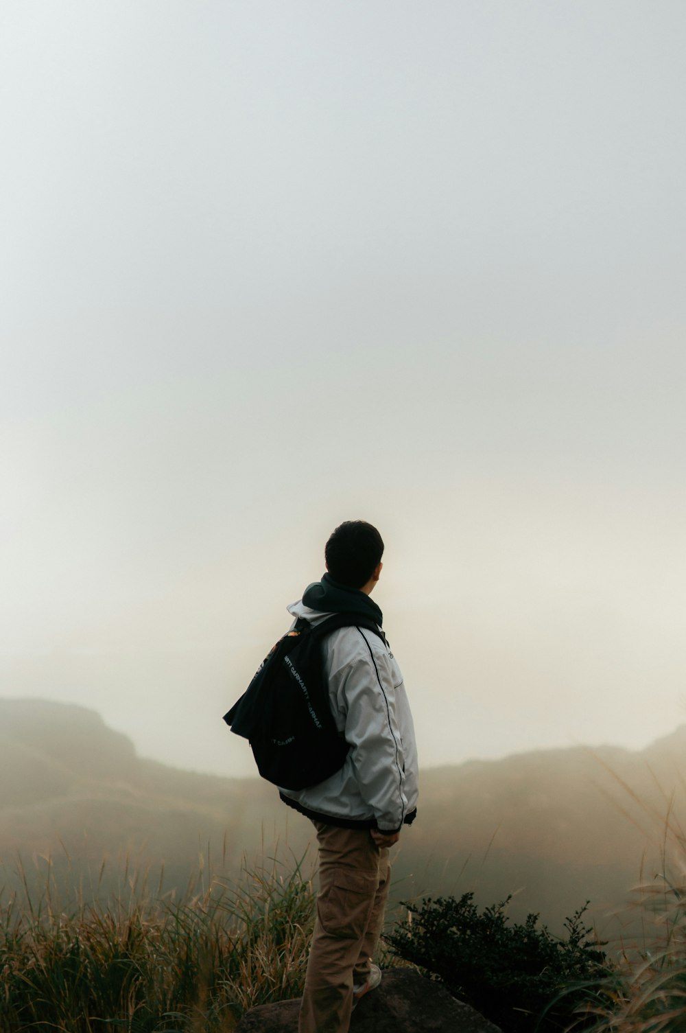 Un uomo in piedi sulla cima di una collina con uno zaino