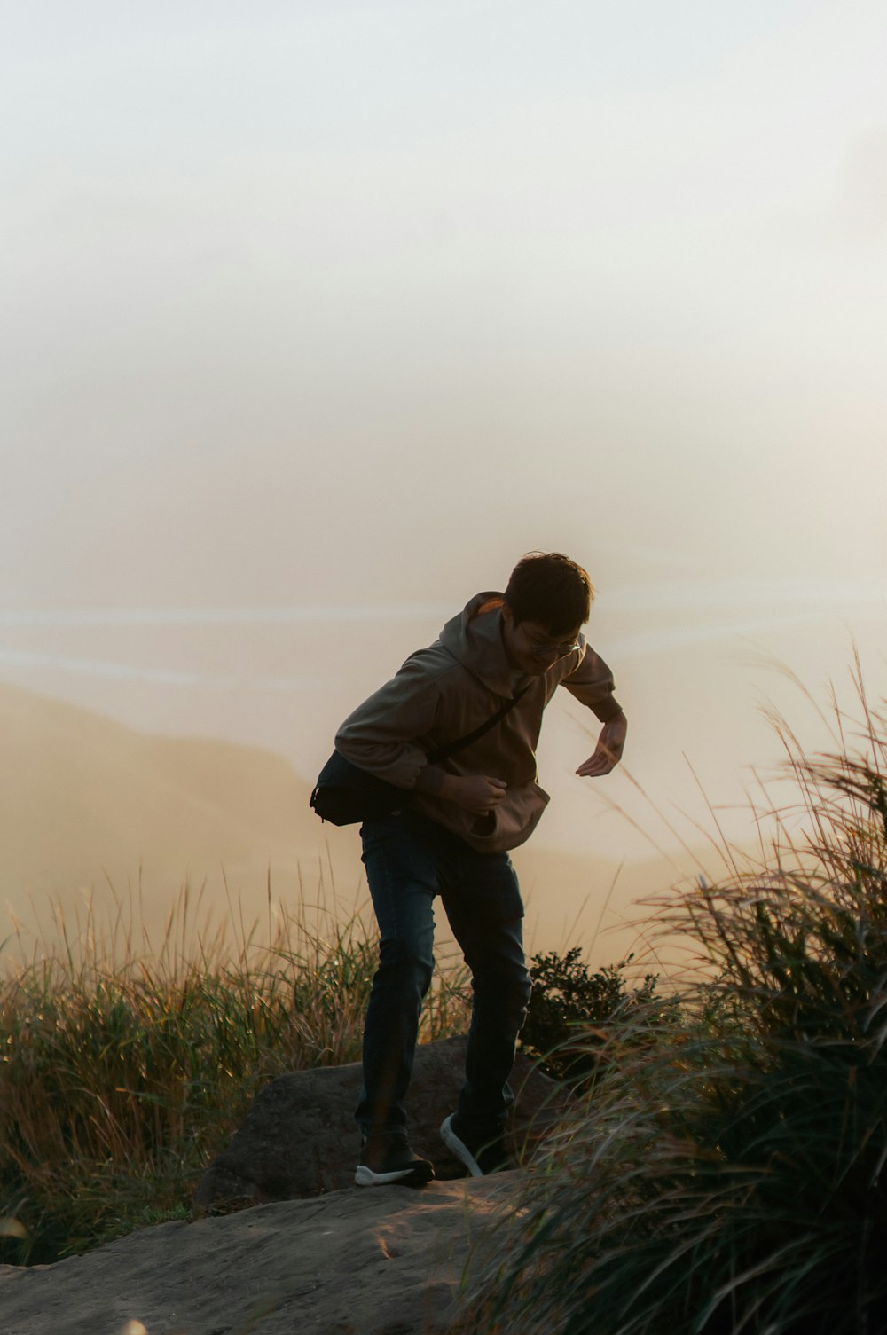 a man standing on top of a hill holding a fish