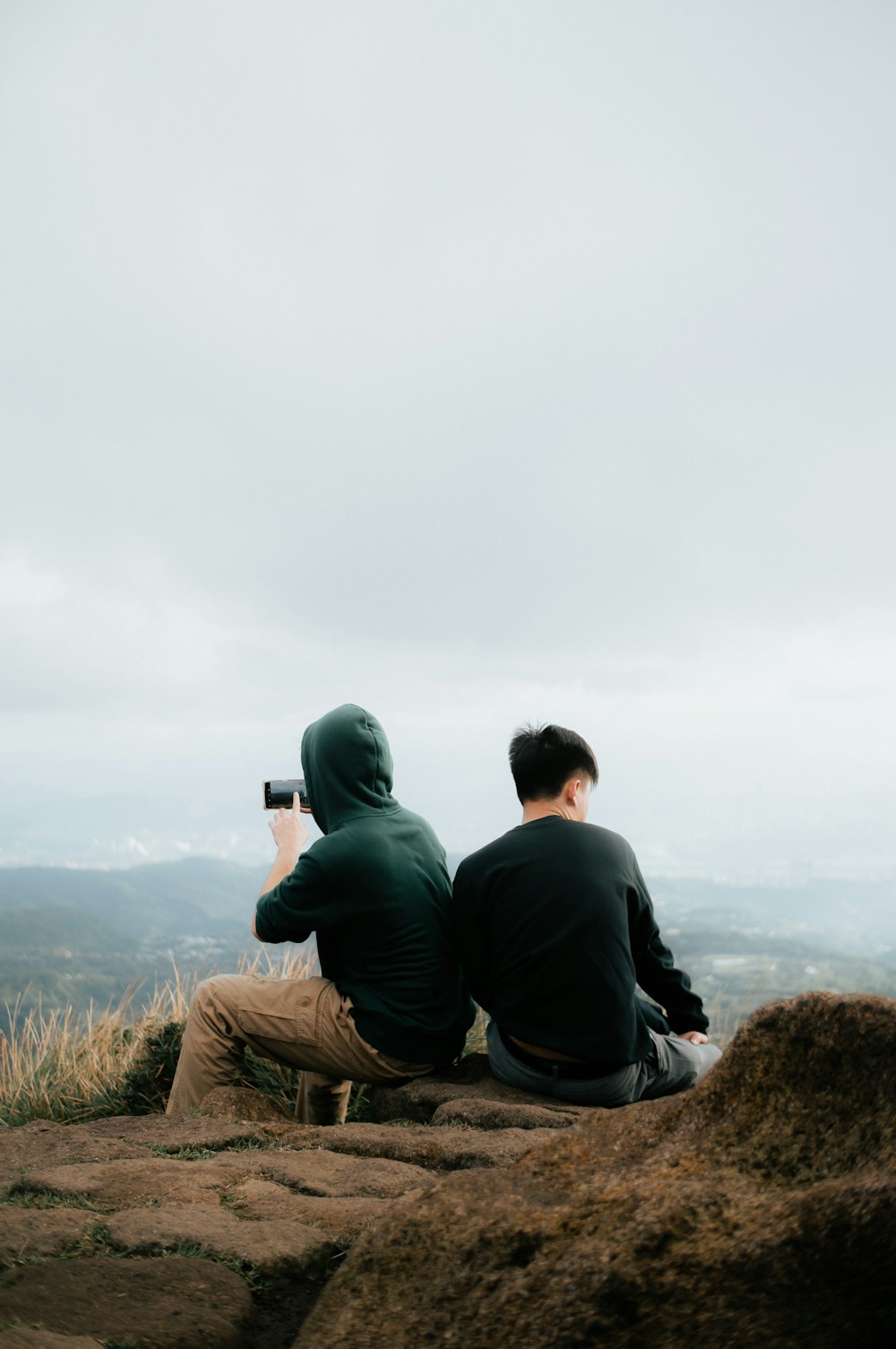 Due persone sedute su una roccia che scattano una foto