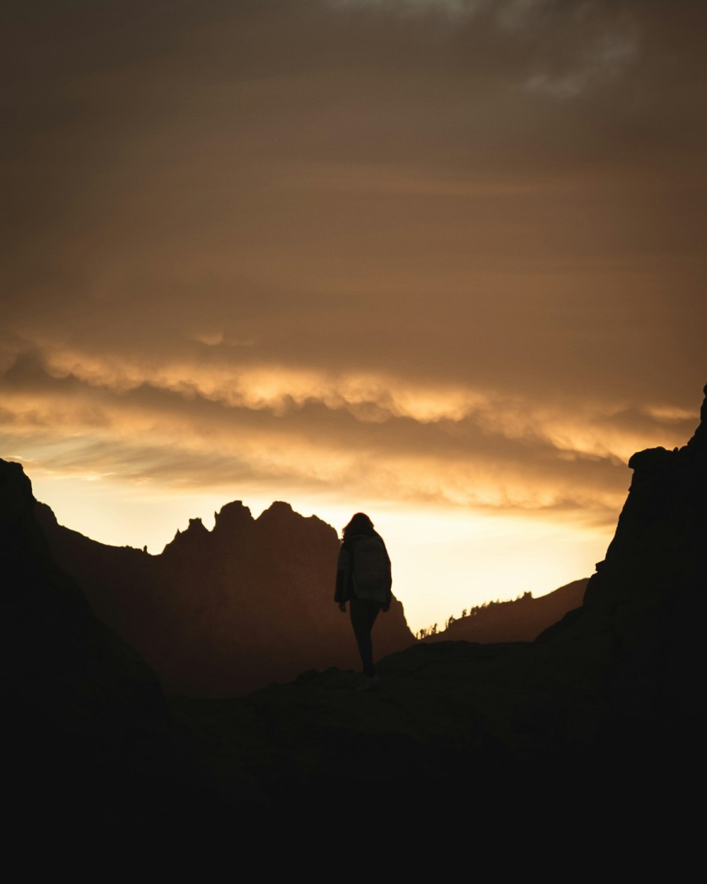 a person standing on top of a mountain under a cloudy sky