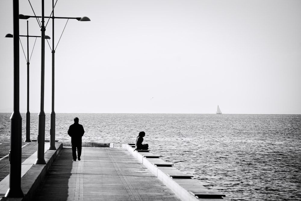 a man walking down a pier next to the ocean