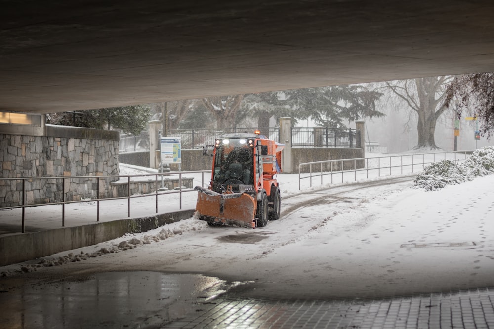a snow plow is parked under a bridge