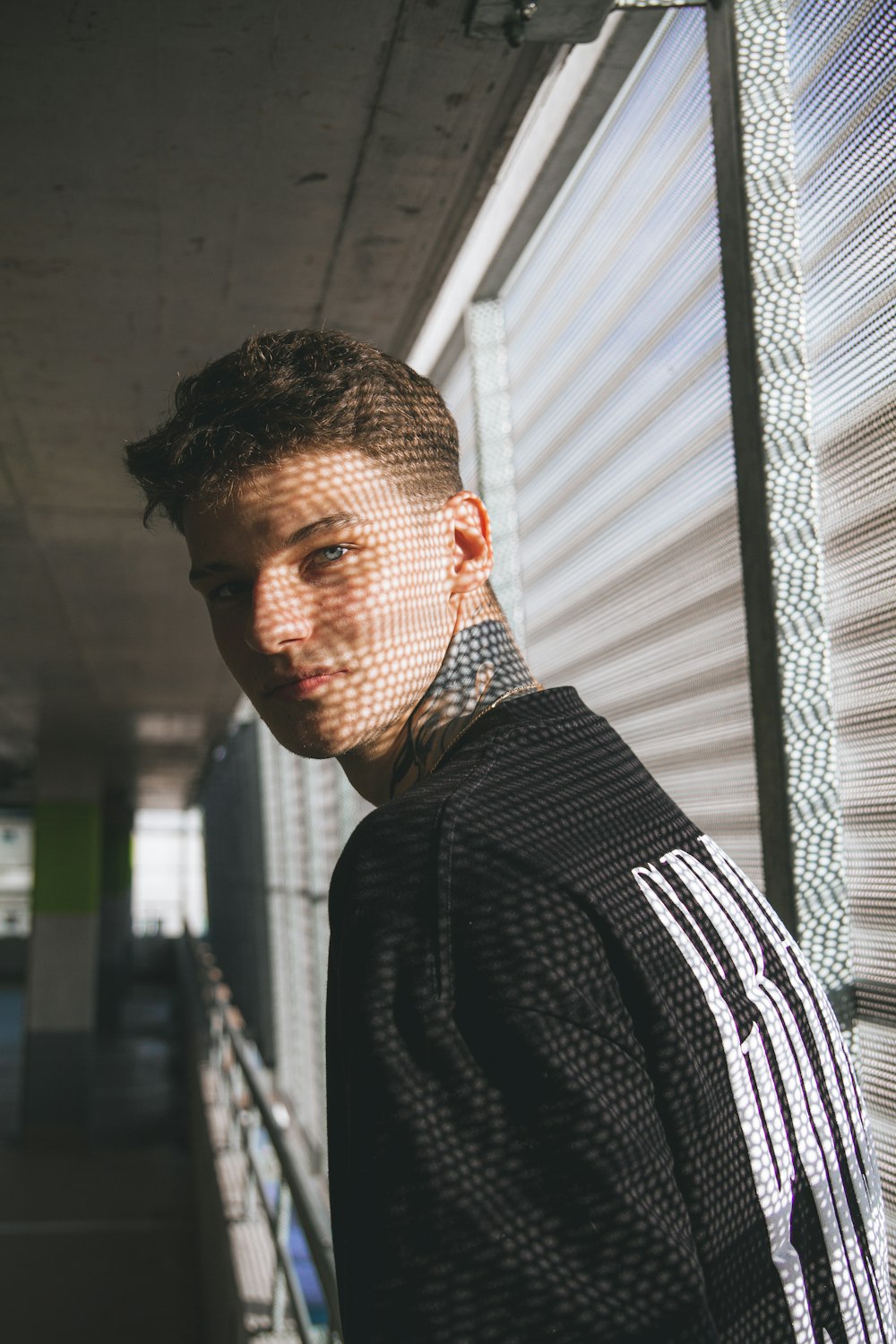 a young man with tattoos on his neck standing in front of a building