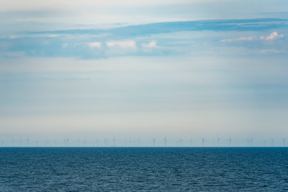 a large body of water with wind mills in the background