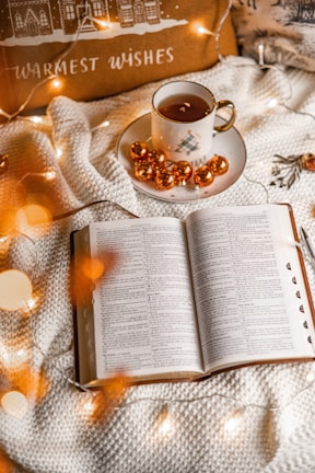 A cozy night scene with a steaming cup of tea and a book of jokes.
