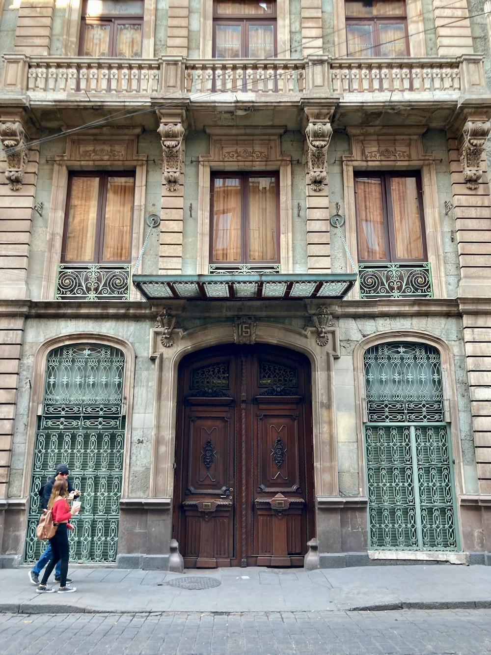 a woman walking down a street past a tall building