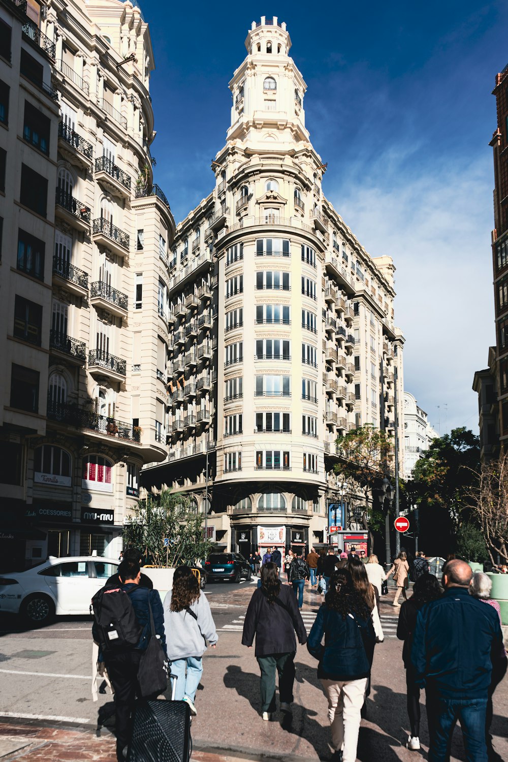 a group of people walking down a street next to tall buildings