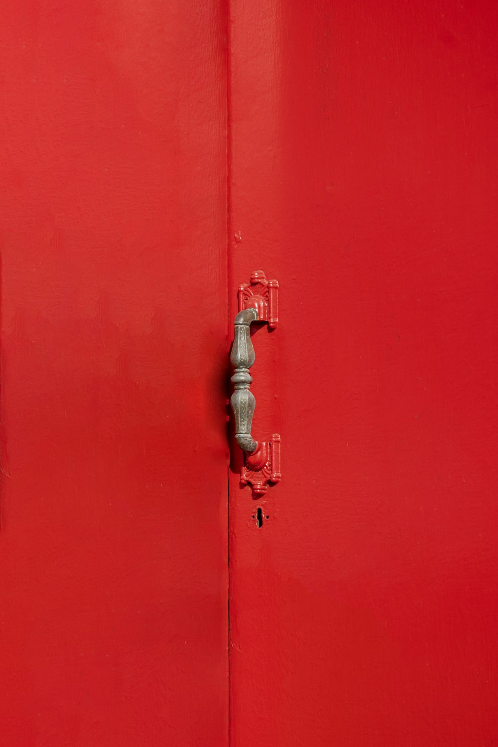 Un primer plano de una puerta roja con una manija de metal
