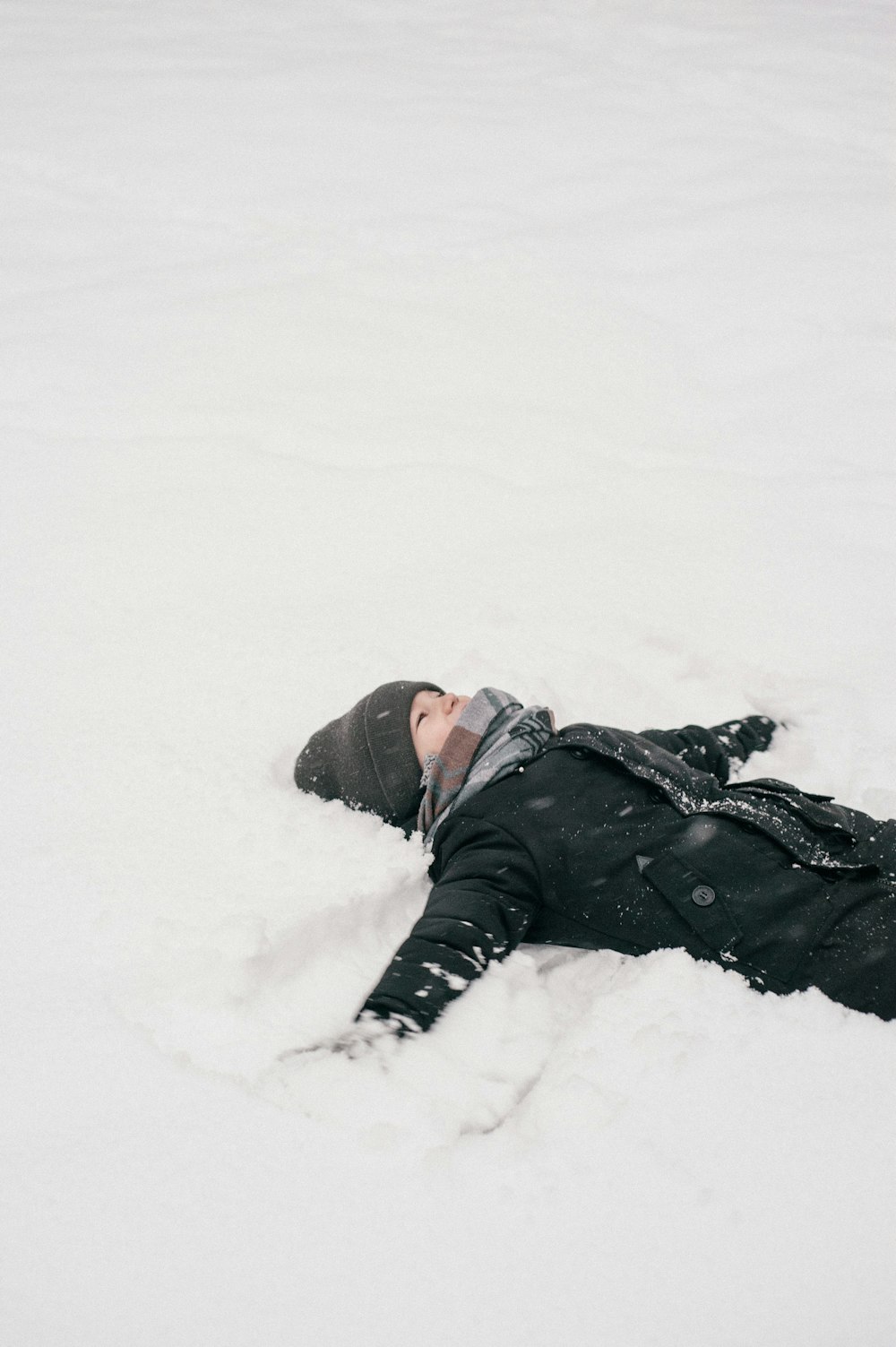 a person laying in the snow with a hat on