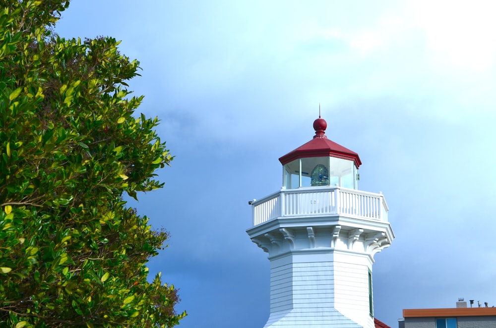 a white lighthouse with a red top on a cloudy day