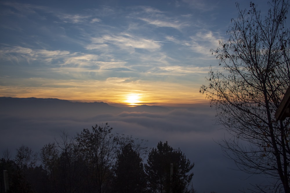 the sun is setting over a foggy valley