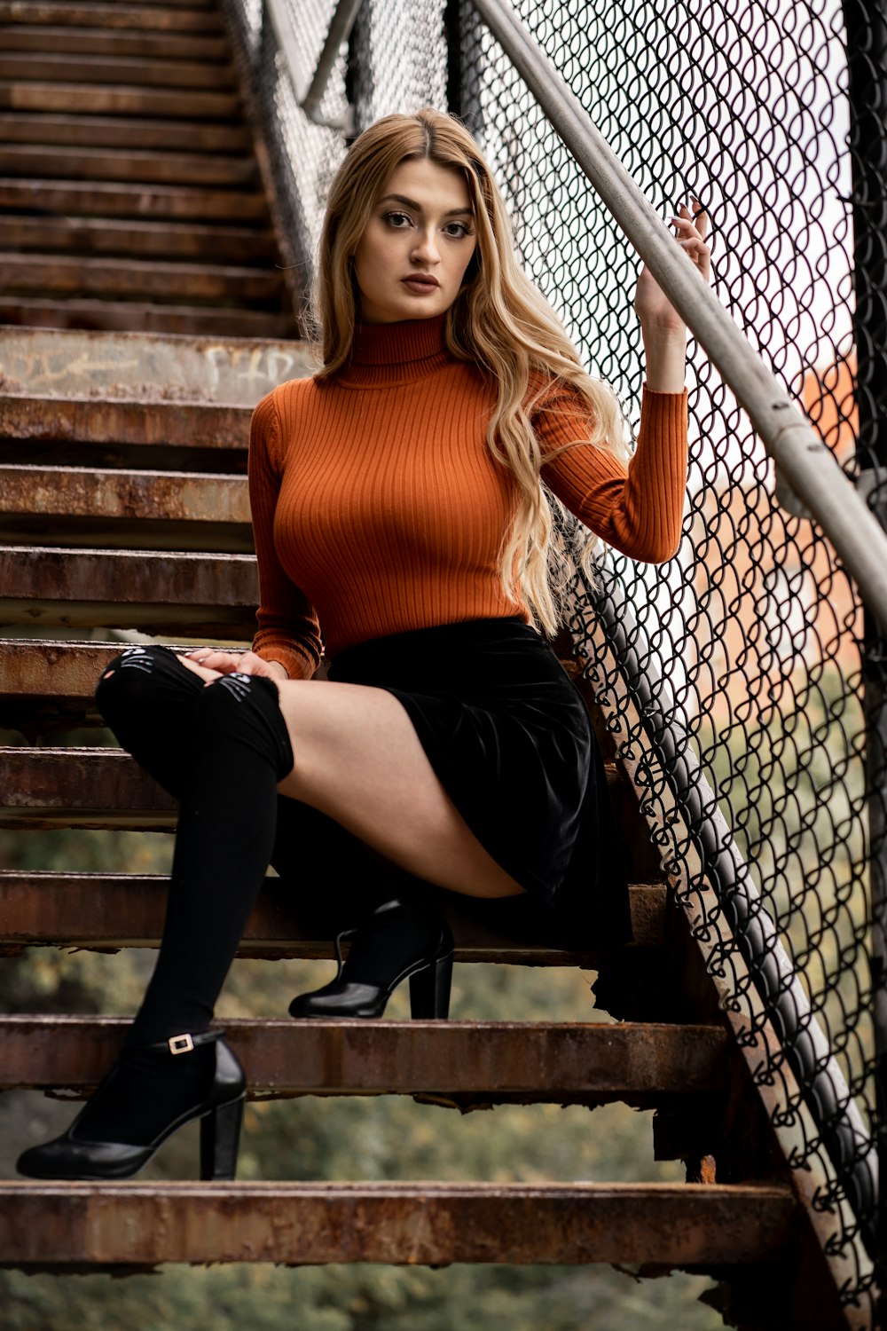 a beautiful young woman sitting on top of a set of stairs