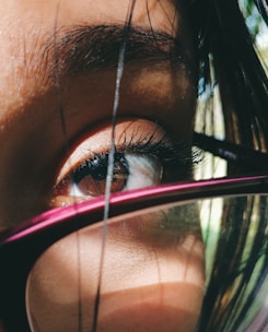 Close-up of an Indian woman wearing sleek purple eyeglasses with a soft pink background.
