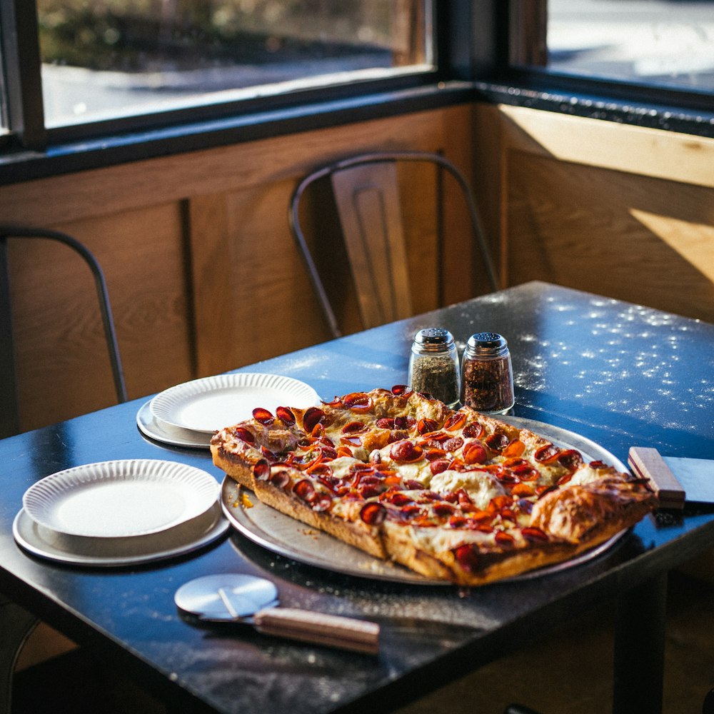 Eine Pizza, die auf einer Metallpfanne auf einem Tisch sitzt