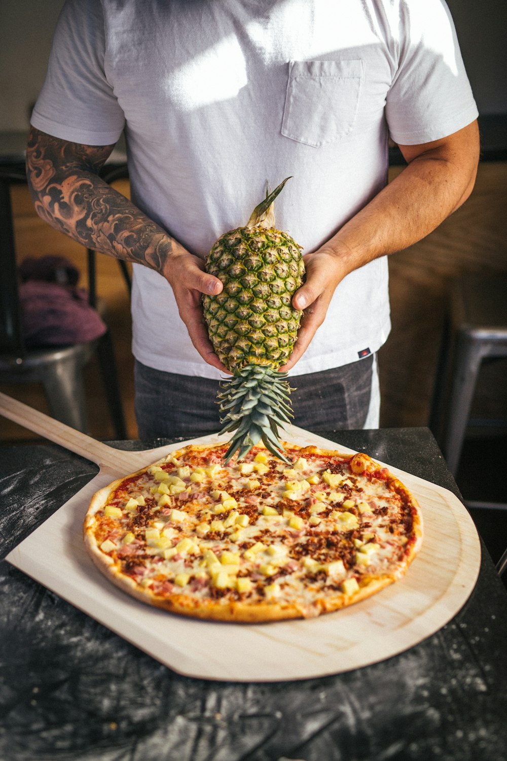 a man holding a pineapple on top of a pizza