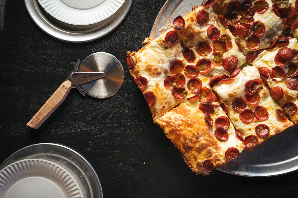 a pepperoni pizza on a plate with a spatula