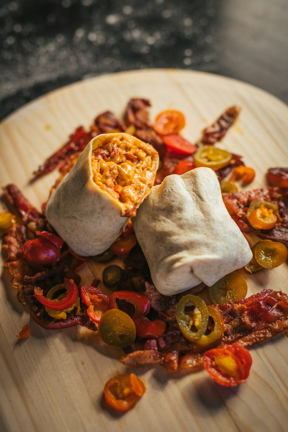 a wooden plate topped with a burrito covered in toppings