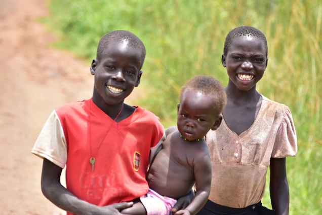 Three children and their elderly grandmother standing outside a worn-down rural house, hopeful and smiling.