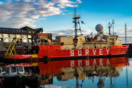 a large red boat sitting in a harbor next to a building