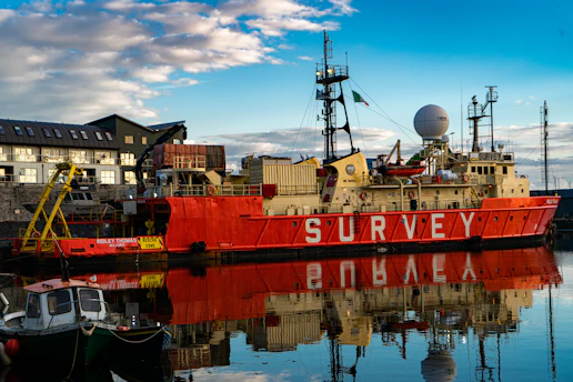 a large red boat sitting in a harbor next to a building