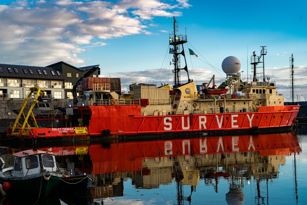 a large red boat sitting in a harbor next to a building