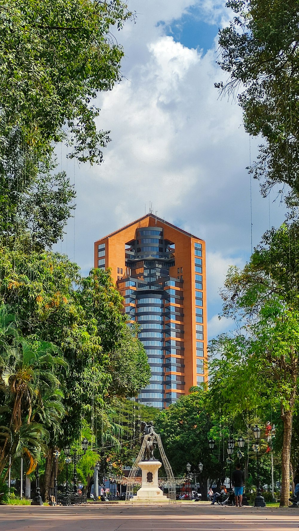 a fountain in the middle of a park with tall buildings in the background