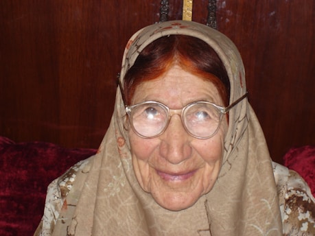 An elderly woman smiling as she participates in a memory game in a cozy workshop setting.