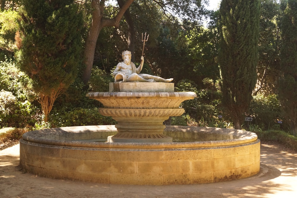 une statue d’une femme assise au sommet d’une fontaine